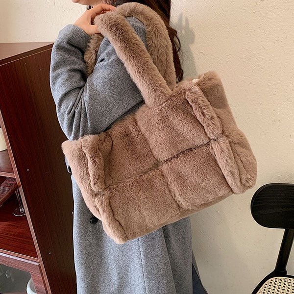 Bruine faux fur handtas, gedragen door persoon in grijze jas. Stijlvolle, zachte schoudertas voor dames, perfect voor wintermode en casual outfits.