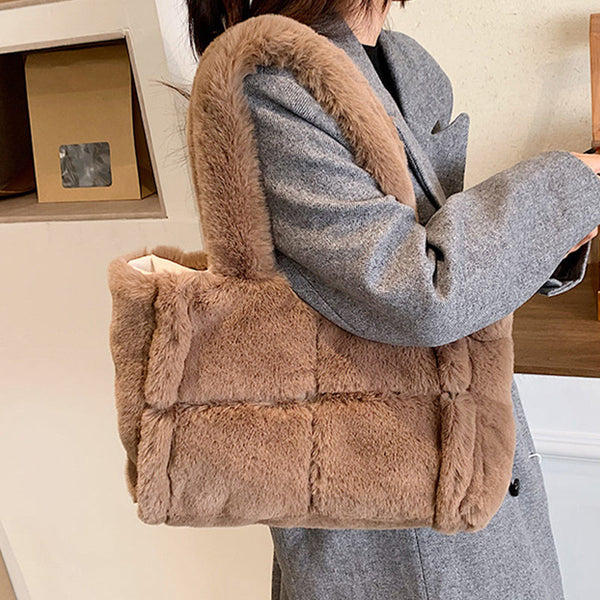 Bruine pluchen schoudertas, gedragen door persoon in grijze jas. Modieuze, zachte handtas voor dames, perfect voor winterse outfits.
