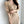 Vrouw in beige gebreide jurk met kabelpatroon en lange mouwen, draagt een parelketting. Stijlvolle herfstmode, elegant en trendy design.