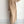 Vrouw in beige gebreide maxi-jurk met kabelpatroon, lange mouwen en split, gecombineerd met pluizige slippers. Stijlvolle herfstmode.