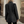 Vrouw in zwarte wollen jas met visgraatpatroon, staand op straat. Stijlvolle wintermode, dameskleding, buitenkleding, trendy jas.