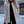 Grijze wollen damesjas, herringbone patroon, elegante wintermode, gedragen door vrouw op straat, stijlvolle outfit, stedelijke achtergrond.