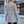 Vrouw in grijze wollen jas met visgraatpatroon, staand op een geplaveide straat in de stad. Stijlvolle wintermode, stedelijke achtergrond.