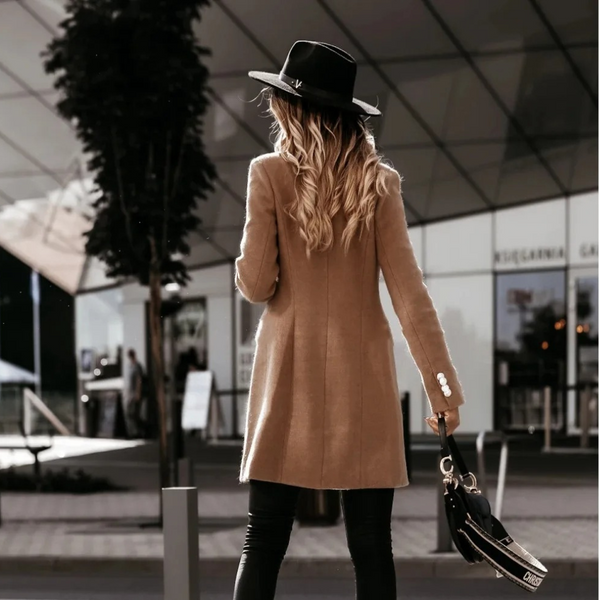 Vrouw in stijlvolle khaki jas en zwarte hoed, loopt buiten bij modern gebouw. Mode, herfstkleding, stedelijke stijl, chique accessoires.
