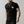 Man in zwart T-shirt met palmboomprint, getatoeëerde armen, zilveren kettingen en horloge. Modieuze herenkleding, casual stijl.