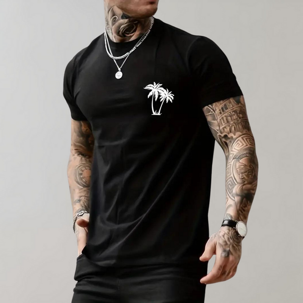 Man in zwart T-shirt met palmboomprint, getatoeëerde armen, zilveren kettingen en horloge. Modieuze herenkleding, casual stijl.