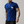 Man in koningsblauw T-shirt met palmboomprint, tatoeages, zilveren kettingen en horloge. Casual mode, herenkleding, trendy stijl.