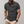 Grijze herenpolo met korte mouwen, knoopsluiting en borstzak, gedragen door man. Stijlvolle casual herenkleding, geschikt voor dagelijks gebruik.