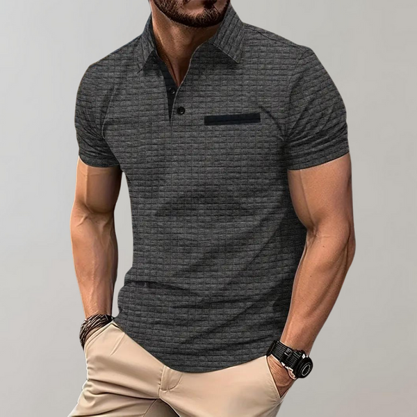 Grijze herenpolo met korte mouwen, knoopsluiting en borstzak, gedragen door man. Stijlvolle casual herenkleding, geschikt voor dagelijks gebruik.