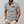 Grijze herenpolo met korte mouwen, zwarte borstzakdetail, gedragen door een man. Stijlvolle casual outfit, ideaal voor mode en comfort.