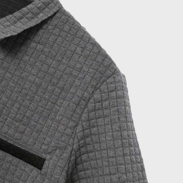 Grijze gewatteerde jas met ruitpatroon, close-up van borstzak en kraag. Stijlvolle herenkleding, moderne wintermode, hoogwaardige stof.
