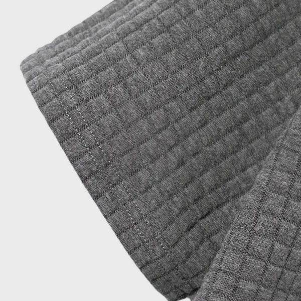 Grijze gewatteerde stof met vierkant patroon, close-up. Ideaal voor interieurdecoratie, textielprojecten en moderne woonaccessoires.