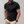 Zwarte polo met bloemenkraag en mouwdetails, gedragen door man met beige broek. Stijlvolle herenkleding, casual en trendy look.