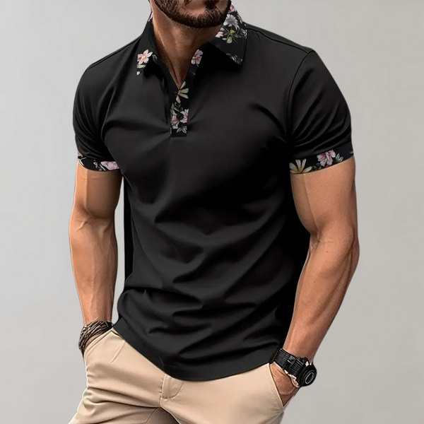 Zwarte polo met bloemenkraag en mouwdetails, gedragen door man met beige broek. Stijlvolle herenkleding, casual en trendy look.
