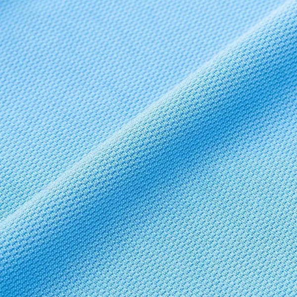 Lichtblauwe piqué stof close-up, textuur en weefsel zichtbaar. Ideaal voor polo's en sportkleding. Hoogwaardige katoenen stof.