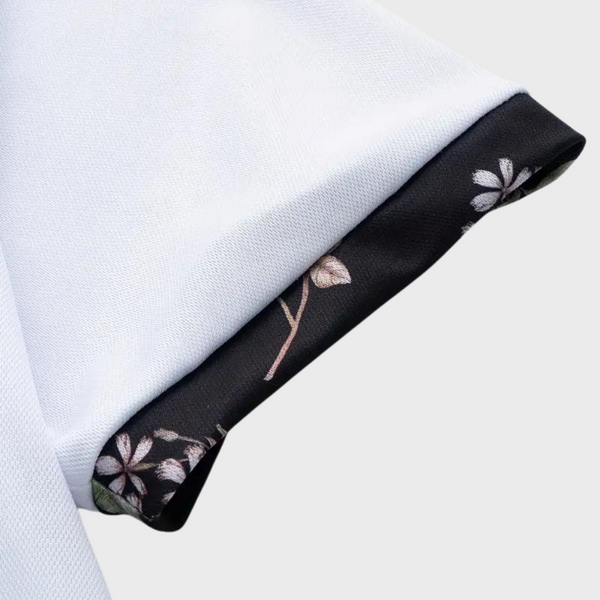 Witte polo met zwarte bloemenprint op de mouwomslag, stijlvolle herenmode, hoogwaardige katoenen stof, trendy en elegant design.