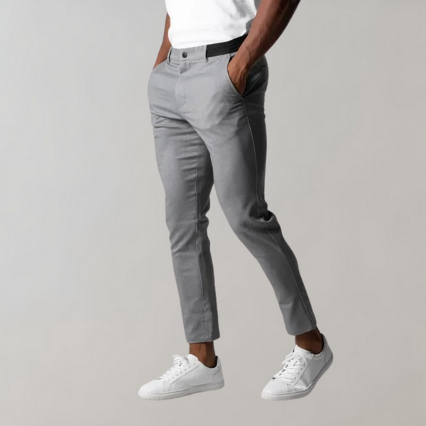 Grijze chino broek voor heren, stijlvol en modern, gecombineerd met witte sneakers. Perfect voor casual en zakelijke outfits. Comfortabele pasvorm.