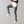 Man in grijze broek en witte sneakers springt in de lucht tegen een neutrale achtergrond. Stijlvolle casual mode, comfortabele kleding.