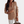 Vrouw in khaki blazer met dubbele rij knopen, witte broek en bruine tas. Stijlvolle damesmode, zakelijke outfit, trendy kleding.