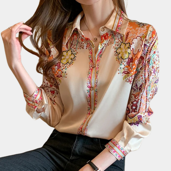 Vrouw draagt beige blouse met kleurrijke bloemenprint, lange mouwen en kraag. Modieuze dameskleding, casual chique stijl.
