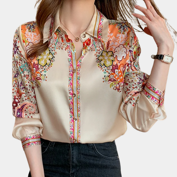 Vrouw draagt zijden blouse met kleurrijke bloemenprint en lange mouwen, gecombineerd met een zwarte broek. Modieuze dameskleding, elegant design.
