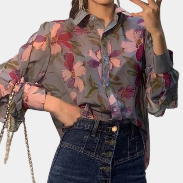 Vrouw draagt kleurrijke bloemenblouse met lange mouwen en knoopsluiting, gecombineerd met hoge taille jeans. Modieuze dameskleding, casual stijl.