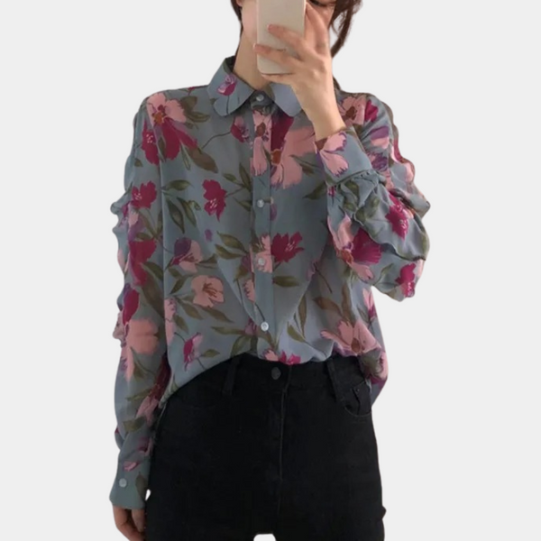 Vrouw in blauwe blouse met roze bloemenpatroon, lange mouwen en knoopsluiting, maakt selfie. Modieuze dameskleding, casual stijl.