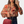 Vrouw in bloemenblouse met lange mouwen, houdt rode tas vast, maakt selfie. Modieuze dameskleding, casual stijl, trendy outfit.