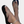 Beige leren sandalen met zwarte zool, gedragen door voeten met witte nagellak en zilveren enkelbandje. Stijlvolle zomerschoenen voor dames.