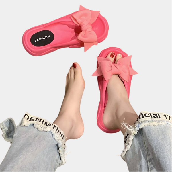 Roze slippers met strik, gedragen door persoon in gescheurde jeans. Modieuze dames sandalen, trendy zomerstijl, comfortabele pasvorm.