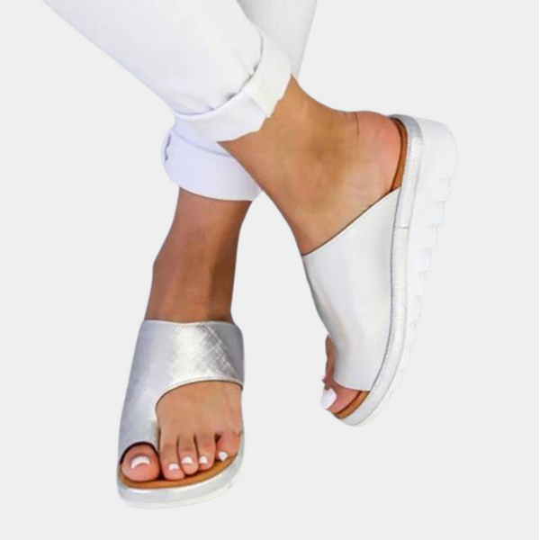 Zilveren damesmuiltjes met open teen, comfortabele witte zool en stijlvol design. Perfect voor zomerse outfits en casual gelegenheden.