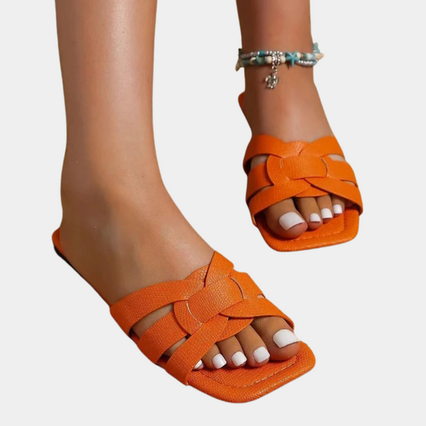 Oranje dames sandalen met gevlochten bandjes en open teen, gedragen met enkelbandje. Perfect voor zomerse outfits en stranddagen.