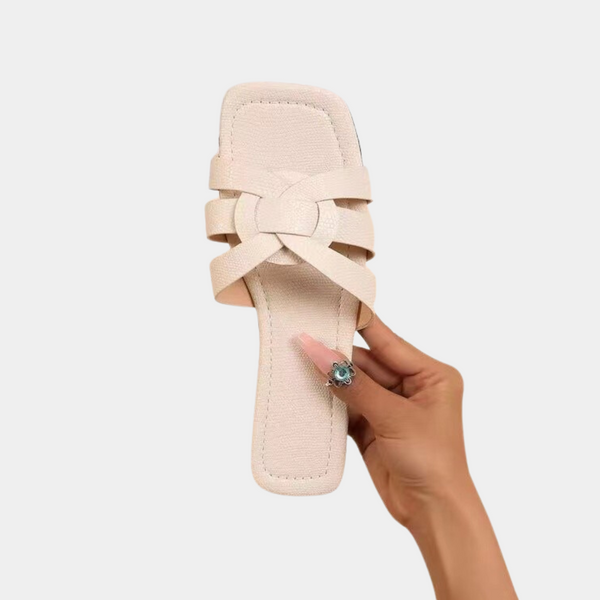 Beige leren damessandaal met vierkante neus en gevlochten bandjes, vastgehouden door een hand. Stijlvolle zomerschoen voor casual en elegante outfits.