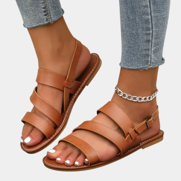 Bruine leren sandalen voor dames met gespsluiting, gedragen met jeans. Trendy zomerschoenen, comfortabel en stijlvol voor casual outfits.