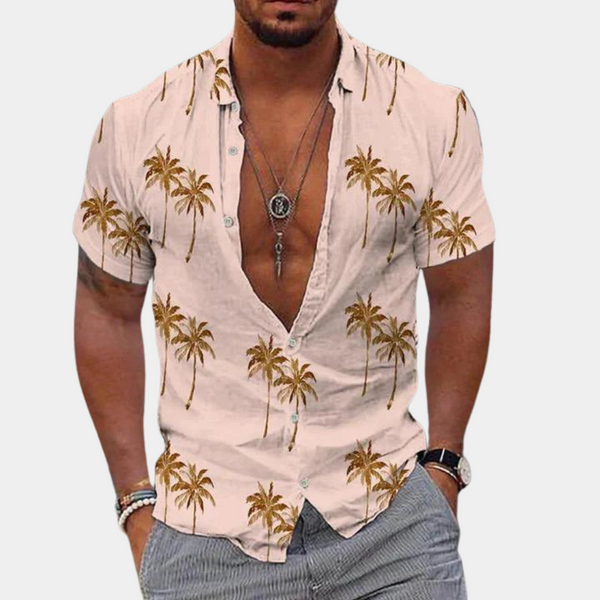 Mannelijk model draagt lichtroze Hawaii-shirt met palmboomprint, open kraag en korte mouwen. Perfect voor zomermode en strandstijl.