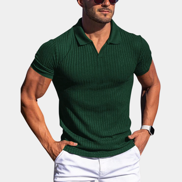 Groene ribgebreide polo voor heren, gedragen door een man met zonnebril en smartwatch, gecombineerd met witte shorts. Stijlvolle zomermode.