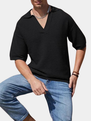 Zwarte herenpolo met korte mouwen en V-hals, gedragen door man met spijkerbroek. Moderne casual herenkleding, geschikt voor zomeroutfits.