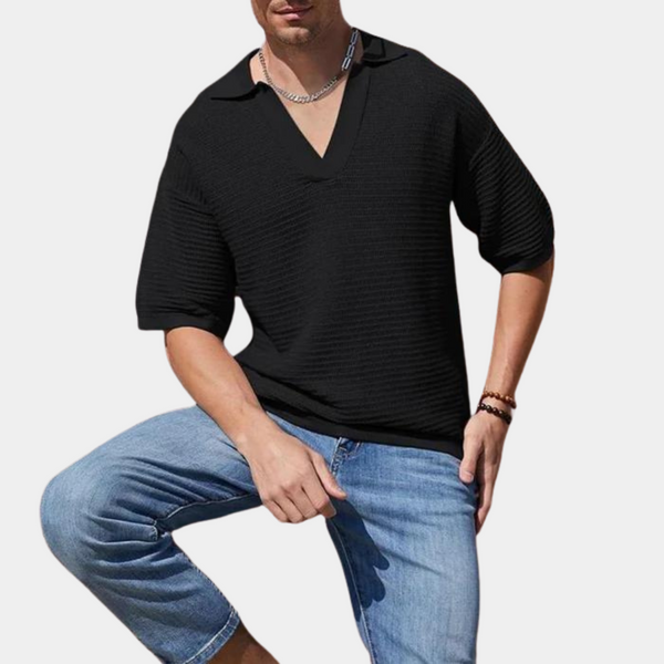 Zwarte herenpolo met korte mouwen en V-hals, gedragen door man met spijkerbroek. Moderne casual herenkleding, geschikt voor zomeroutfits.