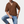 Man in bruine geribbelde trui met korte mouwen en blauwe jeans, poseert tegen witte achtergrond. Modieuze herenkleding, casual stijl.