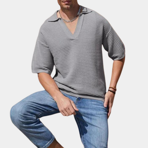 Grijze herenpolo met korte mouwen en V-hals, gecombineerd met blauwe denim shorts. Moderne casual herenkleding, comfortabele zomeroutfit.