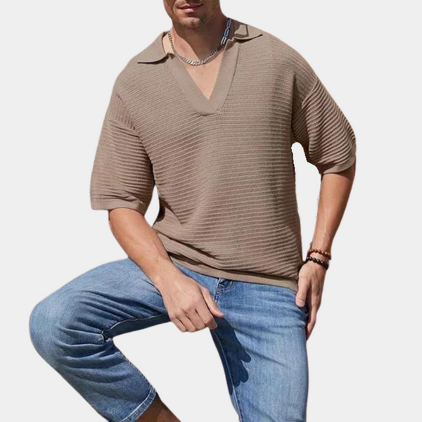 Man in khaki trui met V-hals en korte mouwen, gecombineerd met blauwe denim shorts. Modieuze casual herenkleding, zomeroutfit.