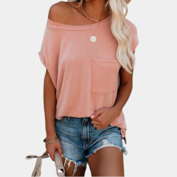 Vrouw in roze off-shoulder top met borstzak en blauwe denim shorts. Casual zomeroutfit, trendy dameskleding, modieuze stijl.