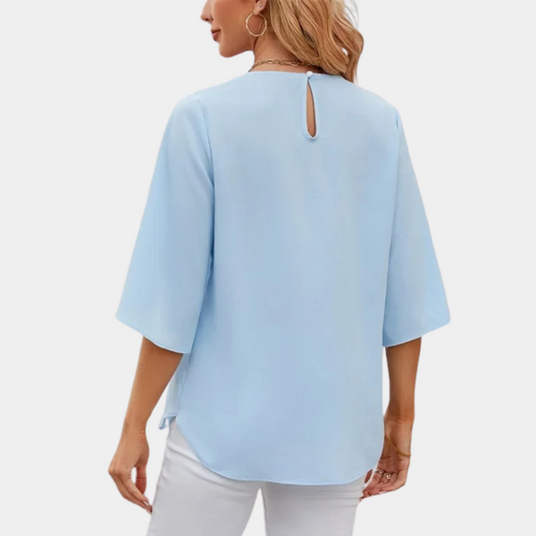 Vrouw in lichtblauwe blouse met driekwart mouwen en knoopsluiting, stijlvolle casual mode, perfect voor lente- en zomerkleding.