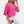 Vrouw in roze blouse met driekwart mouwen en witte broek, houdt een zwarte koffiedop vast. Modieuze dameskleding, casual stijl.