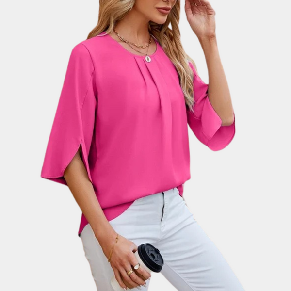 Vrouw in roze blouse met driekwart mouwen en witte broek, houdt een zwarte koffiedop vast. Modieuze dameskleding, casual stijl.
