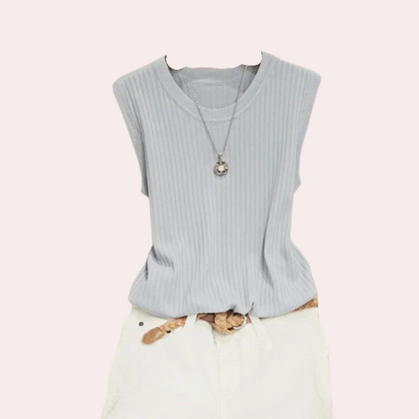 Blauwe geribbelde mouwloze top met ronde hals en zilveren ketting, gecombineerd met witte broek. Modieuze dameskleding, casual zomeroutfit.