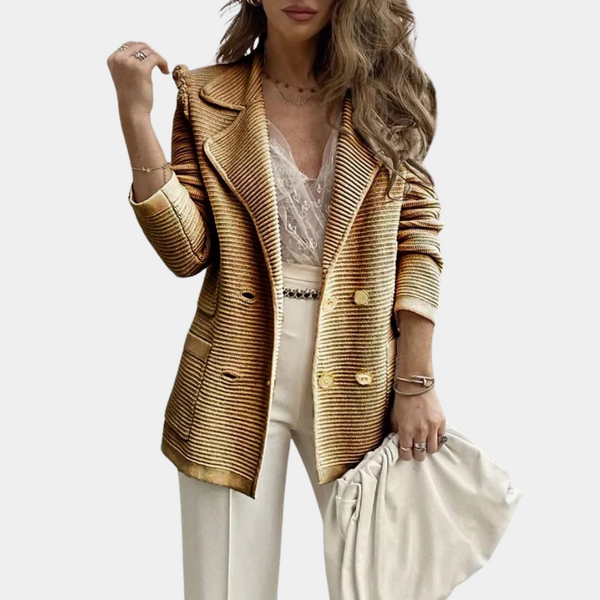 Vrouw in stijlvolle camel blazer met streepjespatroon, witte kanten top en crèmekleurige broek, houdt een bijpassende tas vast. Modieuze dameskleding.