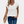 Witte dames T-shirt met V-hals, gedragen met blauwe jeans en beige clutch. Casual mode, zomerse outfit, trendy dameskleding.