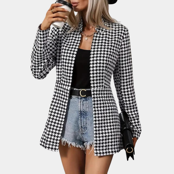 Vrouw in zwart-wit pied-de-poule blazer, zwarte top, denim shorts, hoed, drinkt koffie. Modieuze dameskleding, casual chique stijl.
