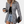 Vrouw in zwart-wit pied-de-poule blazer, zwarte top, denim shorts, met koffie en clutch. Modieuze dameskleding, casual stijl.